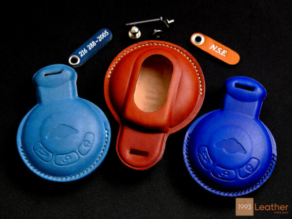 Handcrafted leather key fob covers for Mini Paceman in blue and orange with premium finishing, offering robust protection and personalized options.