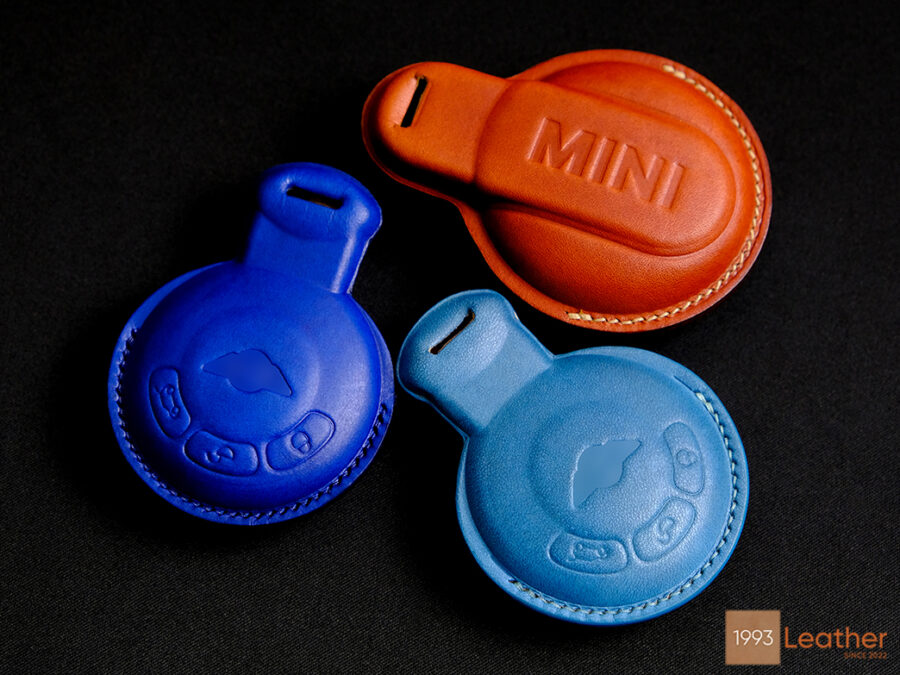 Mini Paceman key fob covers in vibrant blue, orange, and light blue, handcrafted from eco-friendly Veg-tanned leather.