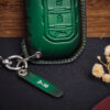 Close-up of green leather Jeep Gladiator key fob cover with engraved leather tag and stitched edges