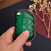 Green leather Jeep Gladiator key fob cover held in hand showing embossed Jeep logo and stitched edges