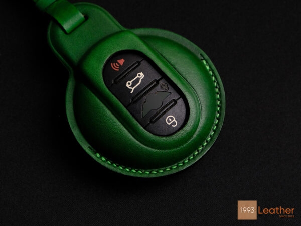 Close-up of precise stitching on handcrafted leather key fob cover for Mini 3-Door Hatch in vibrant green.