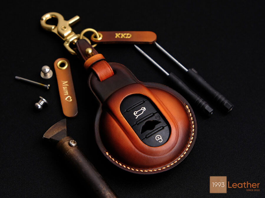 Handcrafted leather key fob cover for Mini 3-Door Hatch with exposed button design and personalized tag.