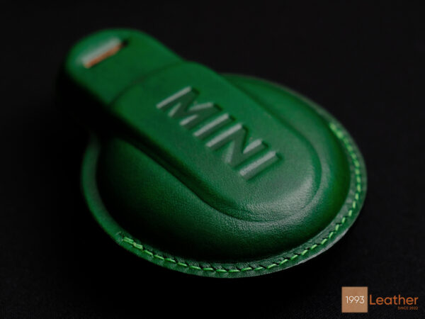 Close-up of precise stitching on a green Mini Countryman leather key fob cover, representing expert craftsmanship