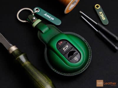 Handmade Patina green leather key fob cover for Mini 5-Door, showcasing meticulous craftsmanship with engraved tag and keychain.