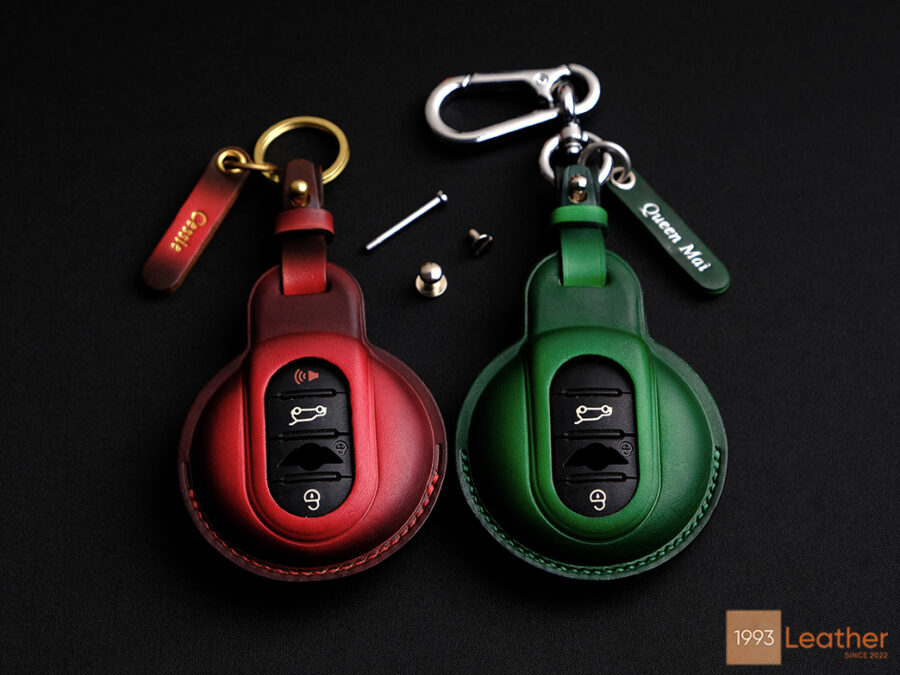 Front view of Mini JCW leather key fob covers in red and green with exposed button design for easy access.