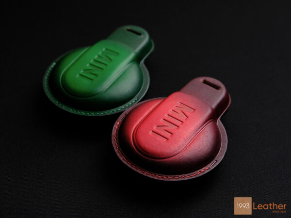 Rear view of Mini JCW leather key fob covers in green and red with embossed MINI logo