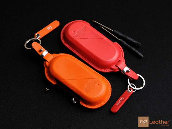 Vibrant red and orange Mini Cooper SE key fob covers made of premium veg-tanned leather.