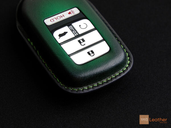 Close-up view of Honda Passport key fob cover highlighting its precise and elegant green stitching details.