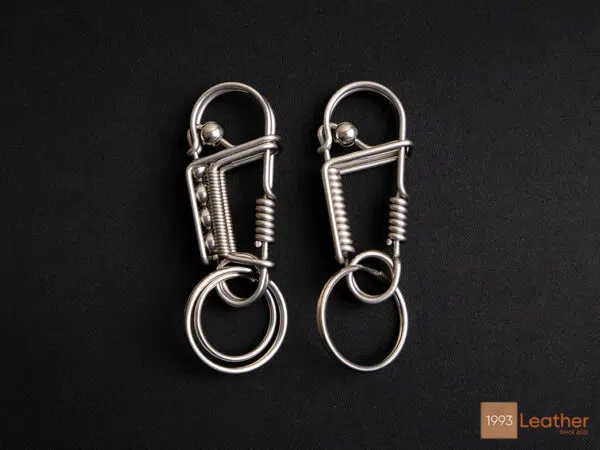 A pair of stainless steel keychains with a spring-loaded locking mechanism.