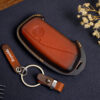 Leather BMW X-Series key fob cover with metal keyring and engraved leather tag displayed on dark background