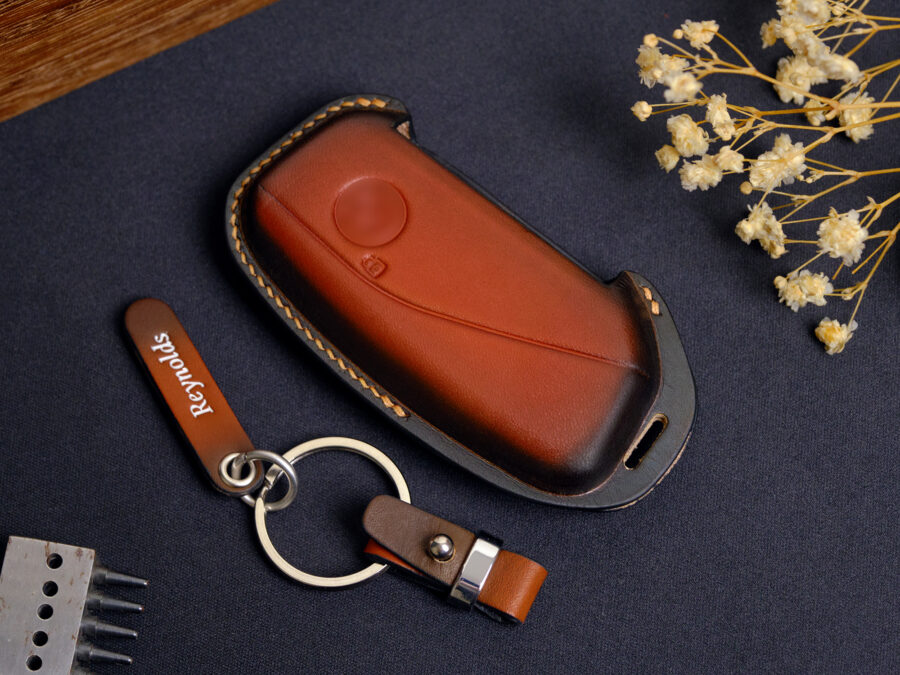 Leather BMW X-Series key fob cover with metal keyring and engraved leather tag displayed on dark background