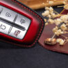 Leather Genesis G-Series key fob cover close-up showing button layout and red contrast stitching