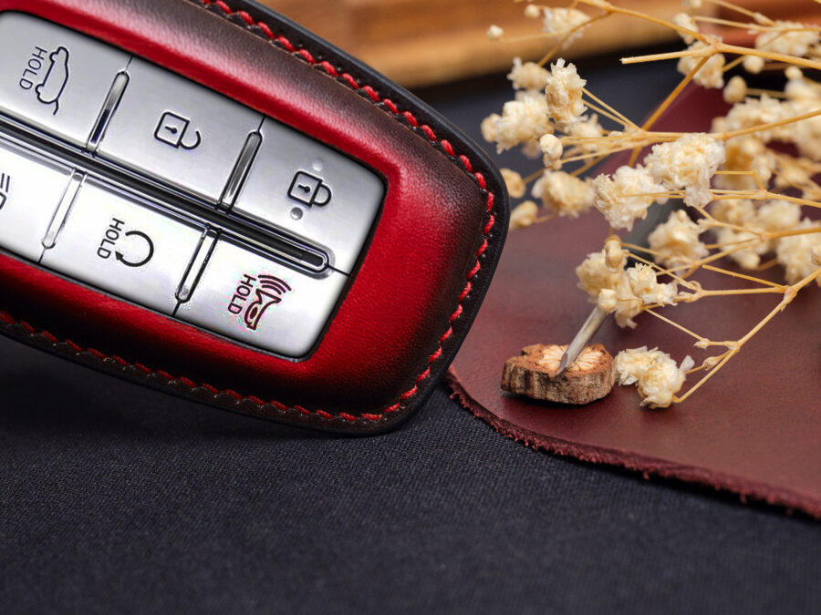 Leather Genesis G-Series key fob cover close-up showing button layout and red contrast stitching