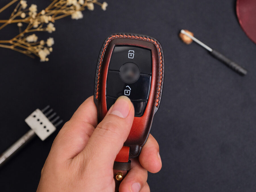 Leather Mercedes S-Class key fob cover held in hand showing button layout and contrast stitching