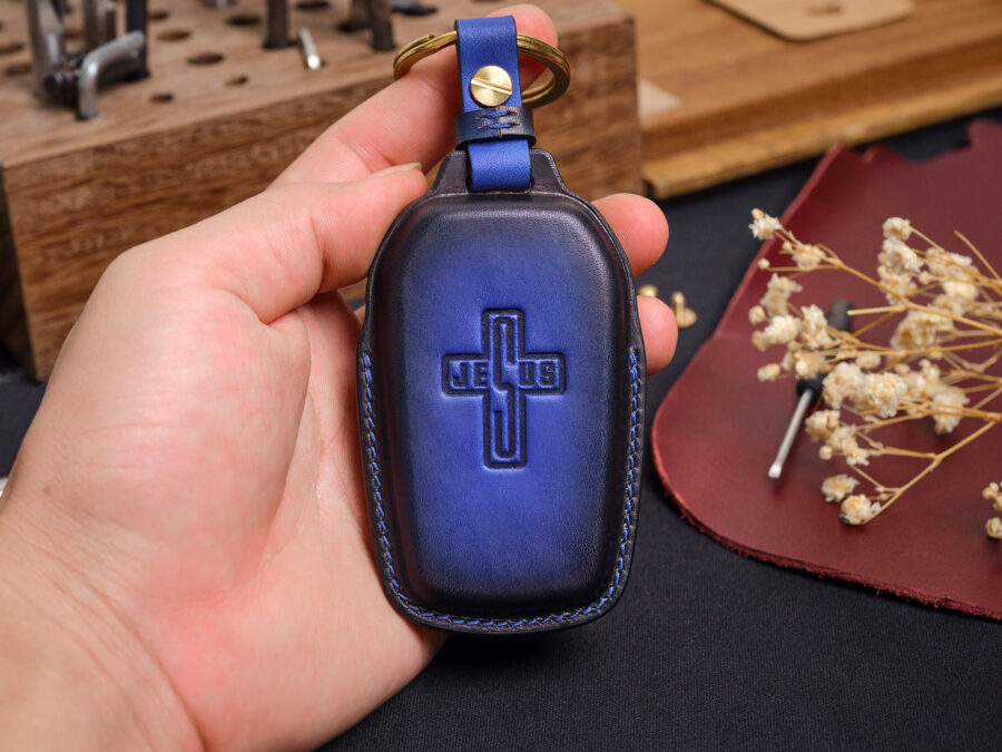 Blue leather Toyota Sequoia key fob cover with embossed logo held in hand showing stitched edges