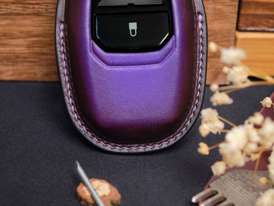 Purple leather Aston Martin Vantage key fob cover close-up showing button area and stitched edges
