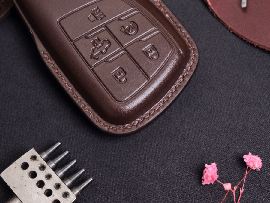 Close-up of leather GMC Sierra key fob cover showing detailed button layout and stitched edges