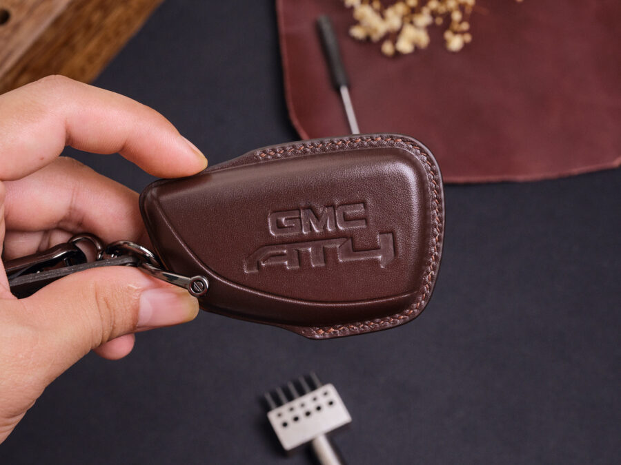 Leather GMC Sierra key fob cover with embossed GMC logo held in hand showing stitched edges