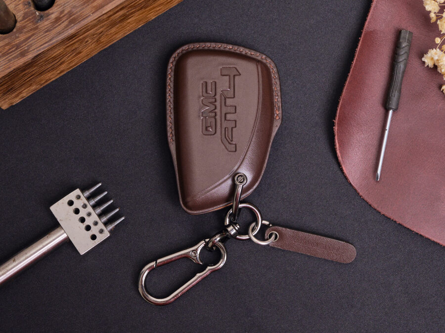 Leather GMC Sierra key fob cover with embossed GMC logo, metal keyring, and leather tag on dark surface