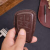 Leather GMC Sierra key fob cover held in hand showing precise button cutouts and stitched edges