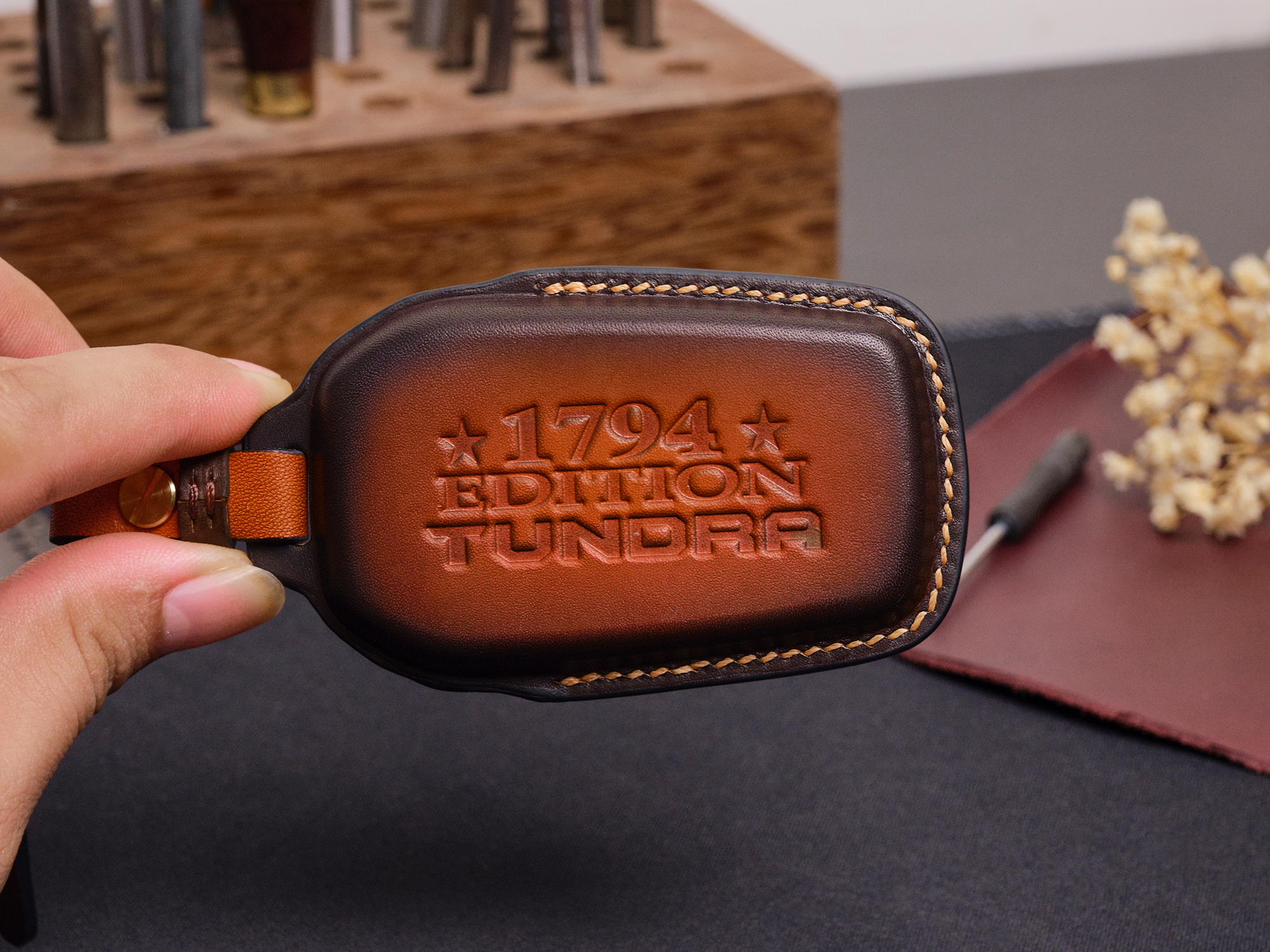 Leather Toyota Tundra key fob cover with embossed Tundra logo held in hand showing stitched edges